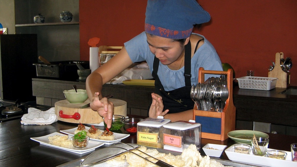 A cooking instructor plating food at a class in Bangkok