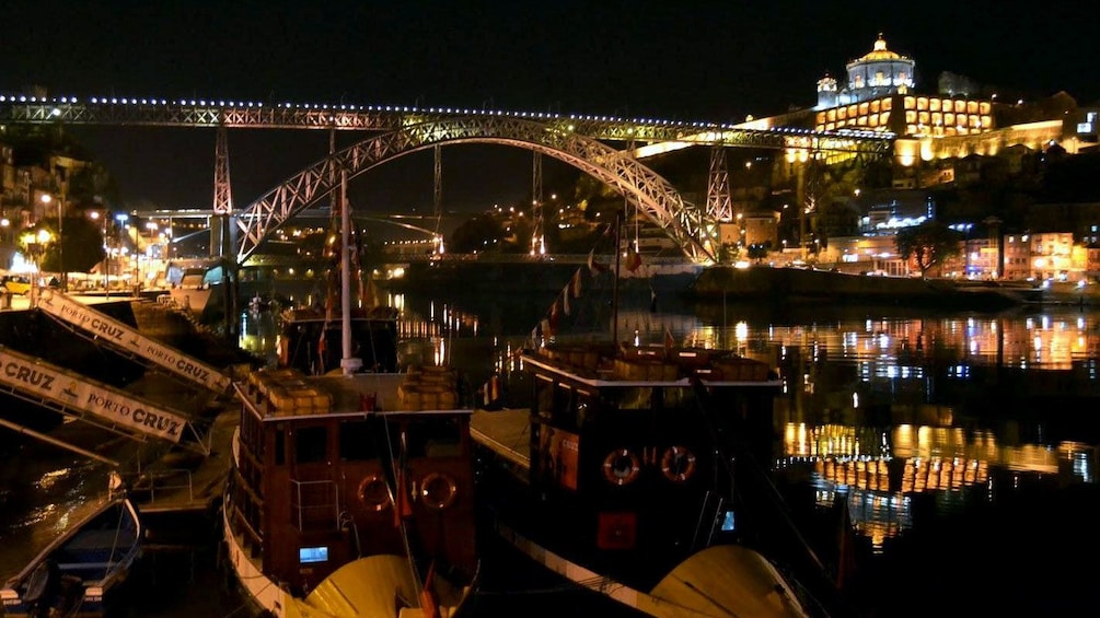 docked boats near the Dom LuÃ­s I Bridge at night in Portugal