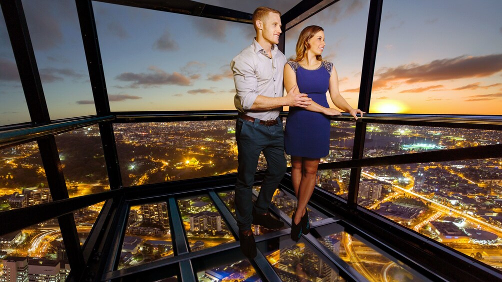 Show item 5 of 7. Couple in the glass cube of The Edge outside the Eureka Skydeck at sunset in Melbourne