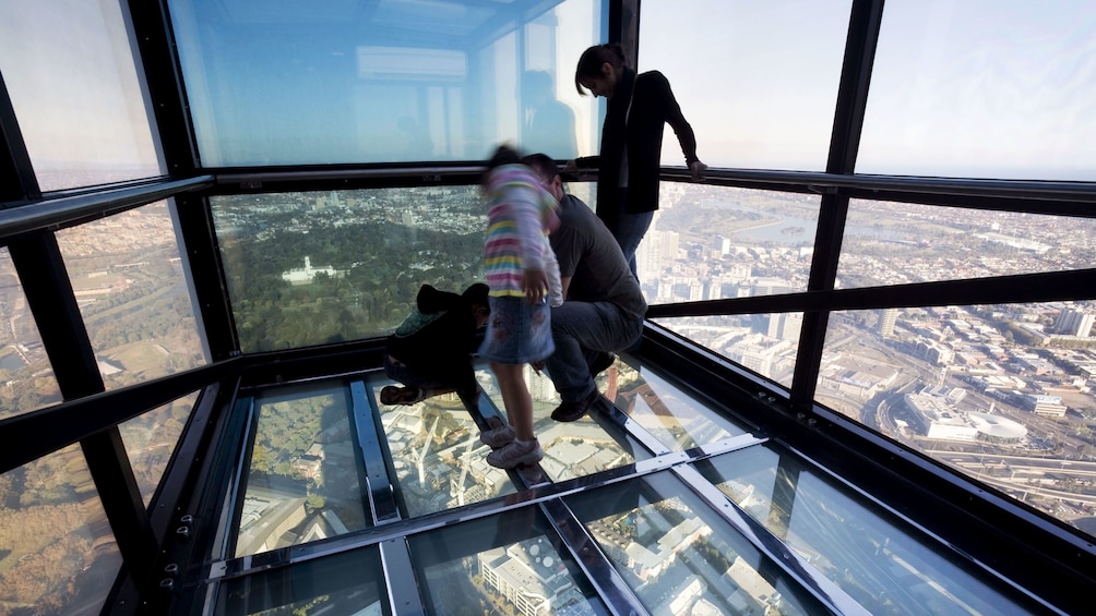 Show item 2 of 7. Family looking through the glass floor of the Edge outside the Eureka Skydeck high above the city in Melbourne