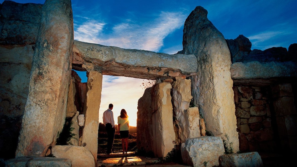 Lataa valokuva 3 kautta 4. couple watching the sunset from the entrance to the prehistoric stone temple in Malta
