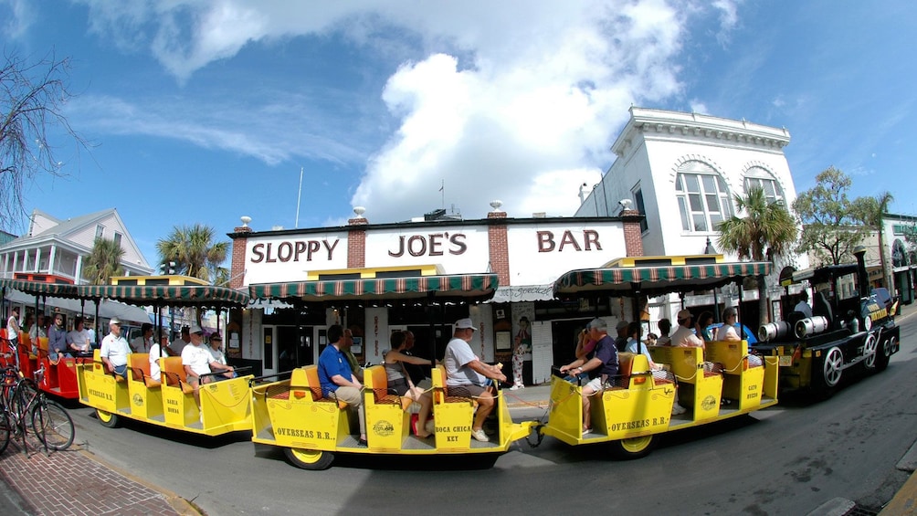 The Conch Tour Train driving along a bar in Key West