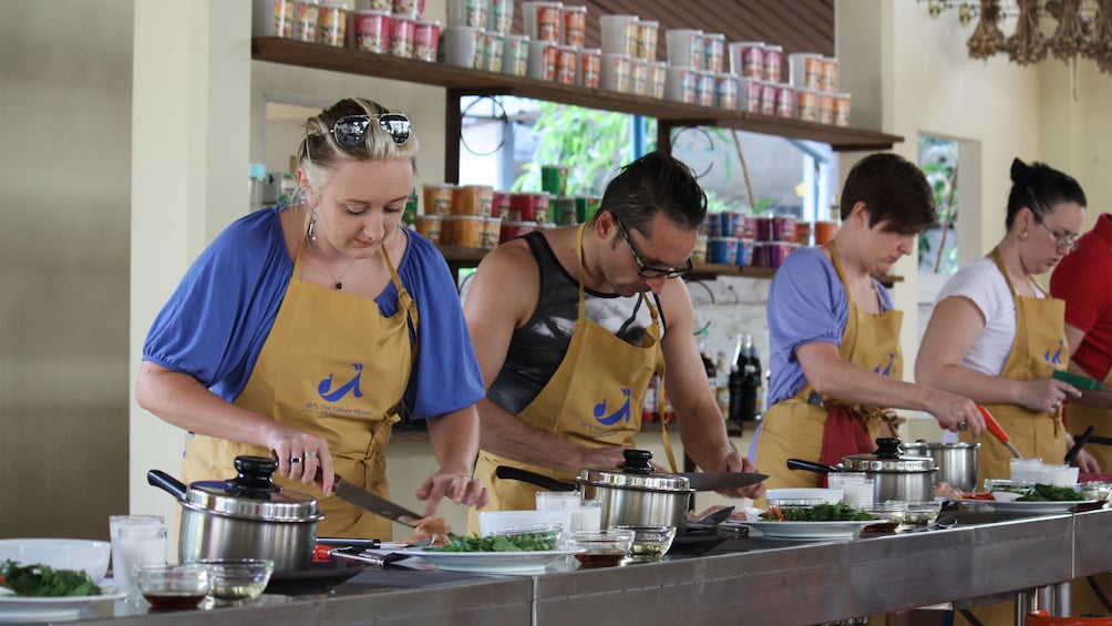 People in aprons cooking at school in Chiang Mai