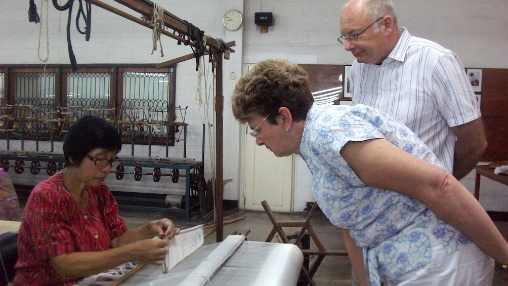 Woman observing a woman working on a loom in Chiang Mai