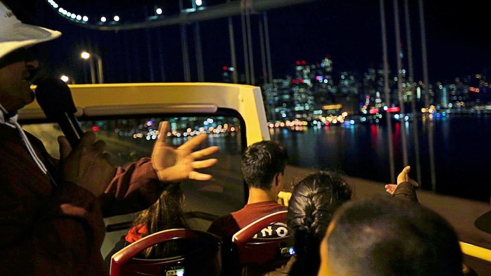 Tour guide with group on sightseeing bus at night in San Francisco