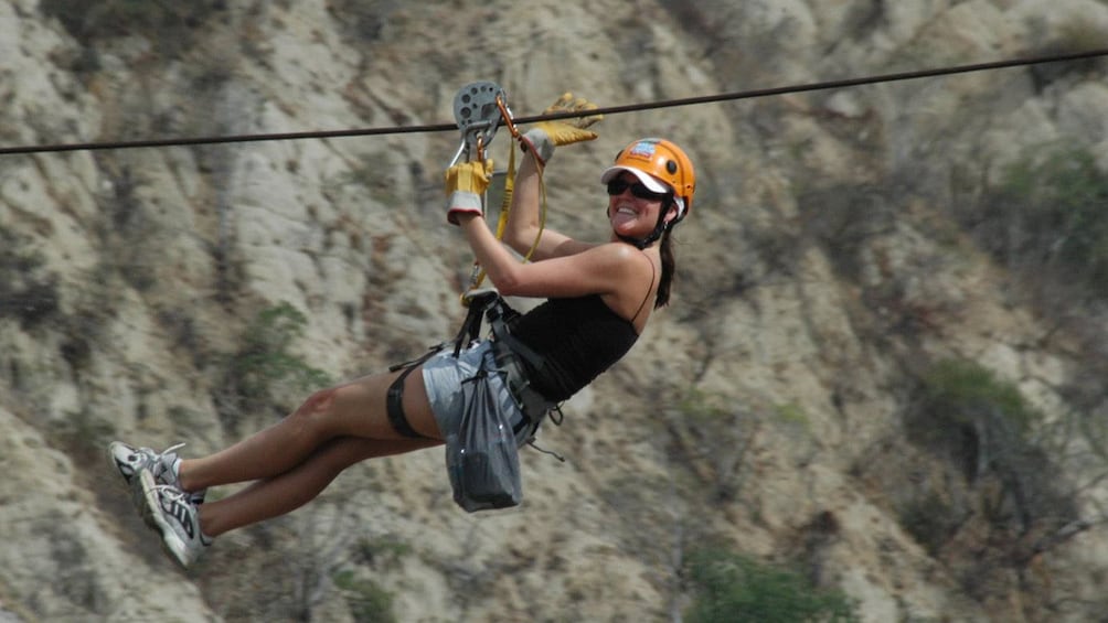 woman zip lining across the ground in Los Cabos