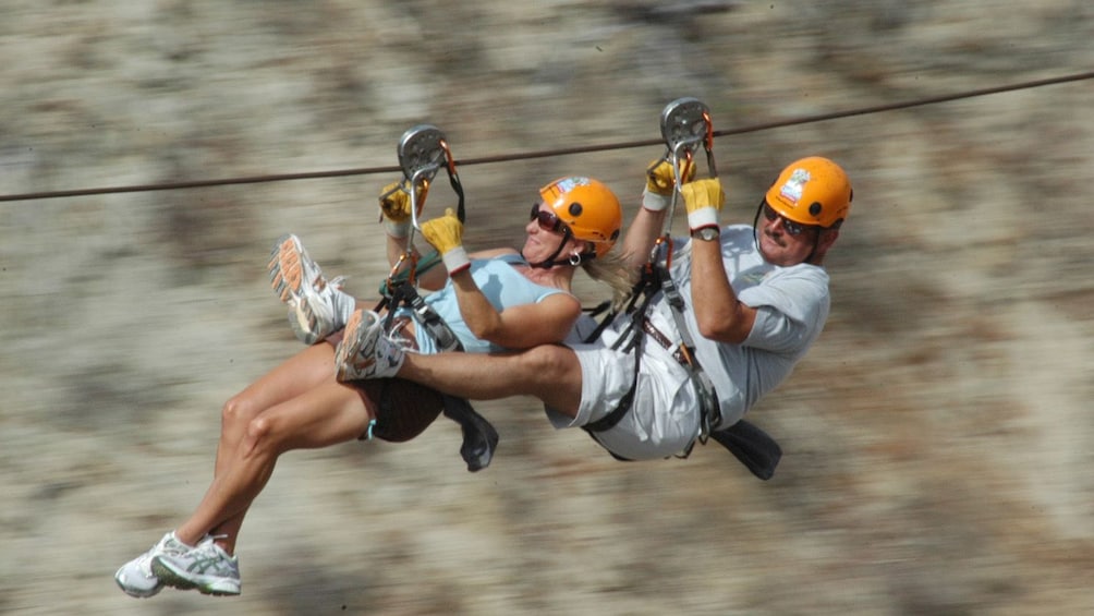 man and woman zip lining across the ground in Los Cabos