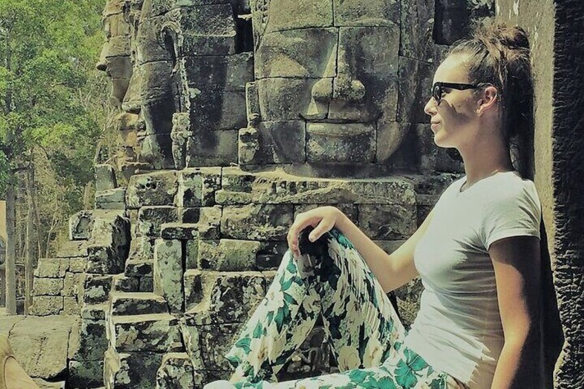 Happy client at Bayon temple with smiling buddha faces in background