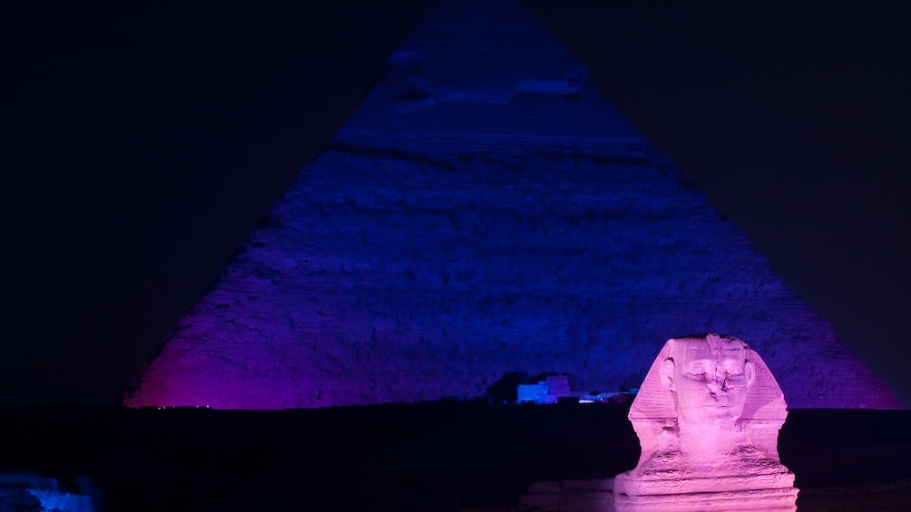 Pyramid and Sphinx lit up in lights at night in Cairo