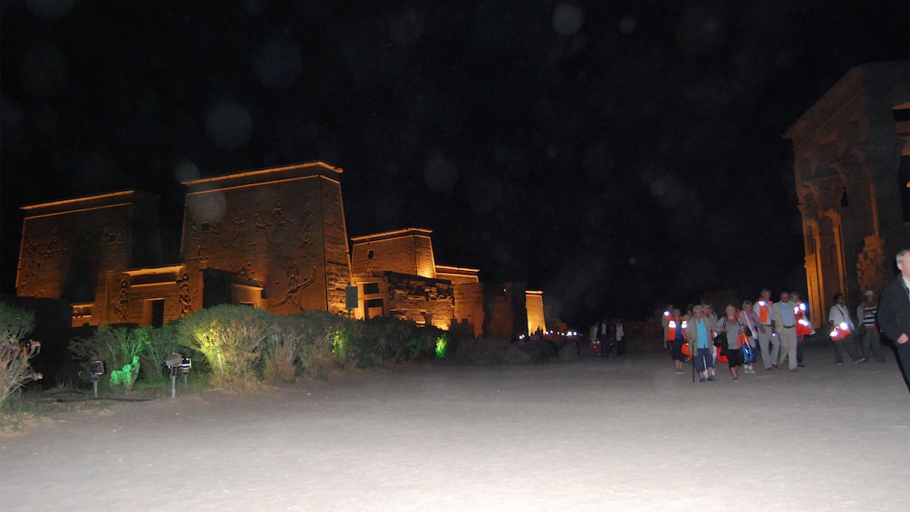Tour group walking by the Philae Temple at night in Aswan