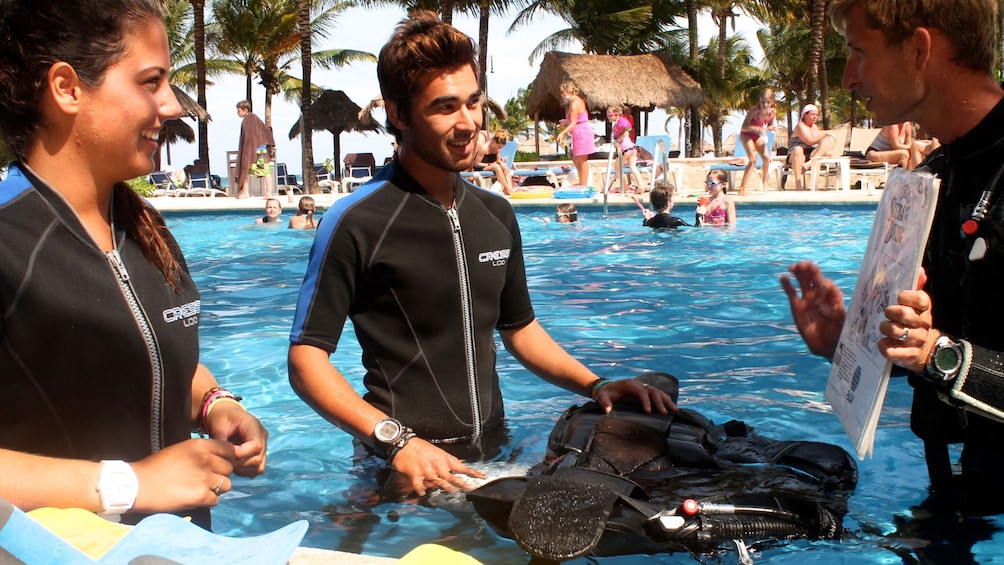 Scuba diving instructor with couple in a pool in Riviera Maya