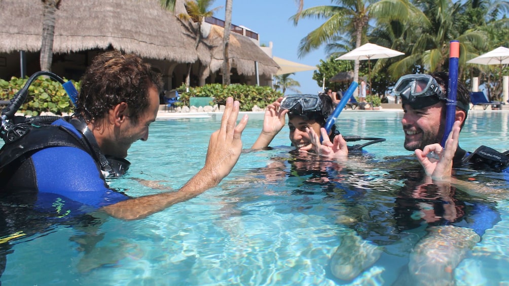 Scuba diving guide going over hand signals with couple in Riviera Maya