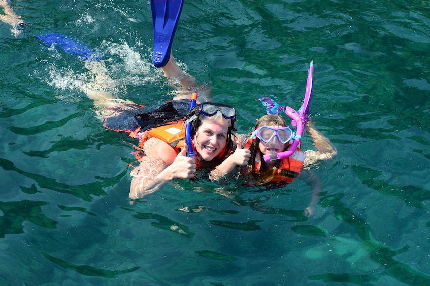 Woman and child give thumbs up while snorkeling