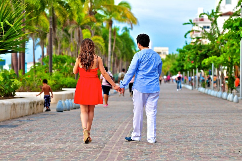 Couple from behind strolling hand in hand on Puerto Vallarta boardwalk