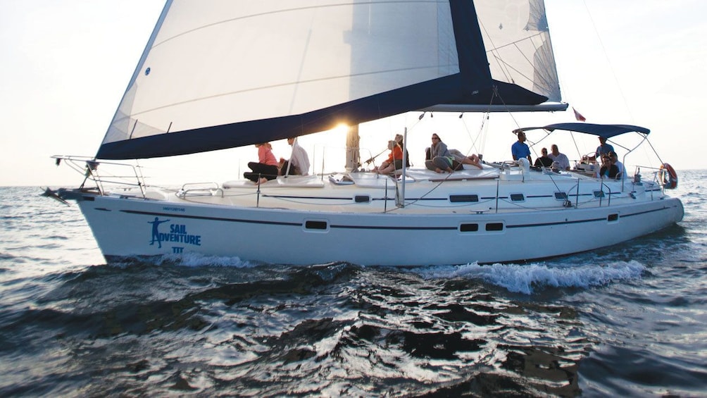Guests enjoy clear skies from the vantage of a luxury sailboat as the sun sets