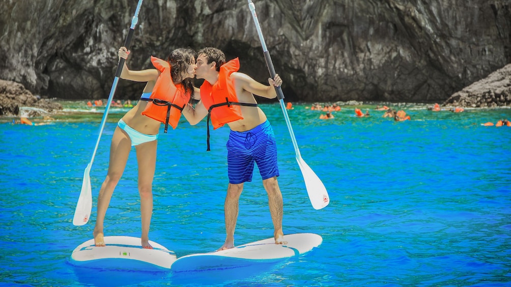 couple kissing from paddle boards