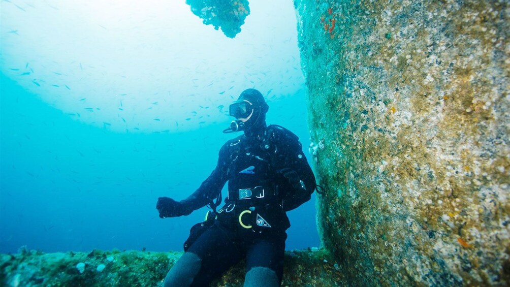 scuba diver sitting on underwater ruins