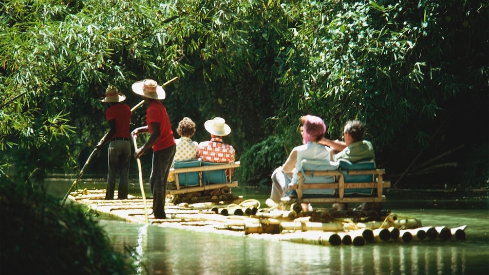 two couples on seats on the bamboo raft with paddlers in the Martha Brae river in Jamaica 