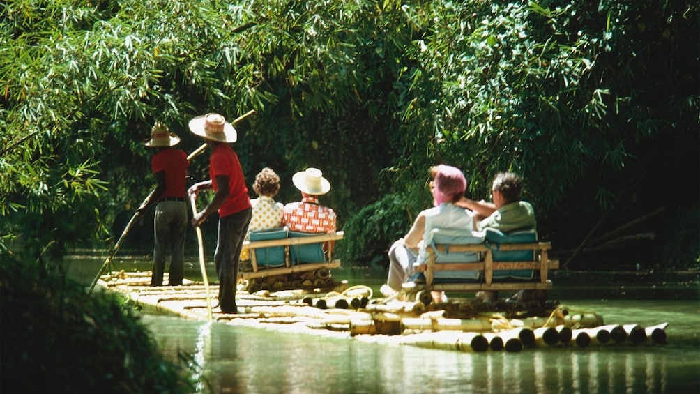 two couples on seats on the bamboo raft with paddlers in the Martha Brae river in Jamaica