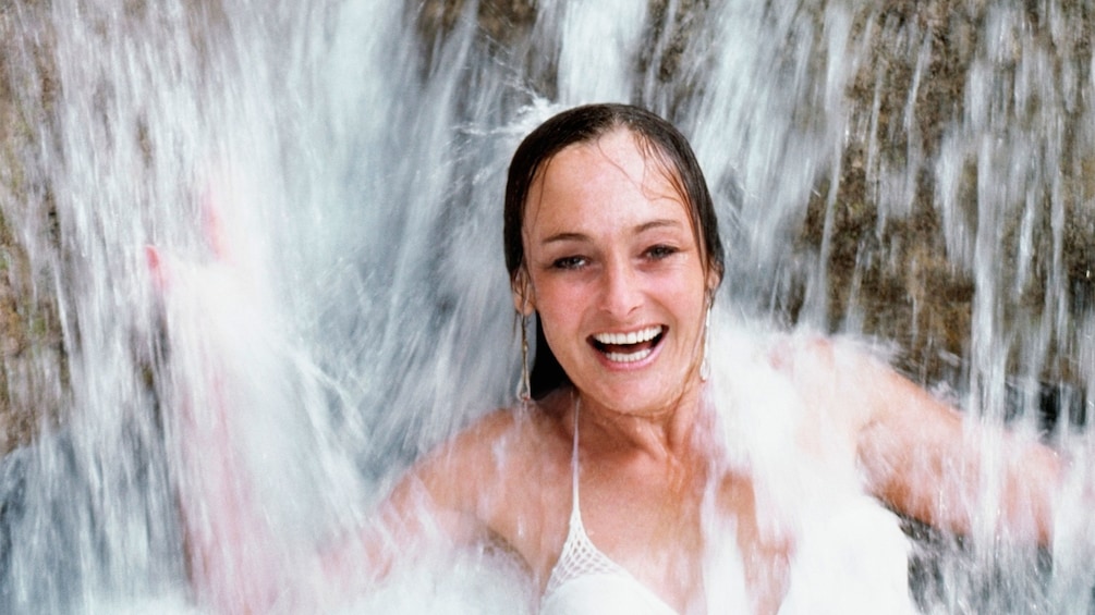 young woman standing in water fall in jamaica