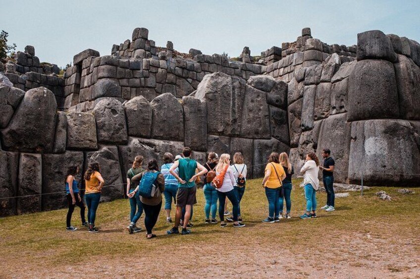 Brightly-dressed onlookers marvel at the giant interlocked stones of Machu Picchu, Peru.