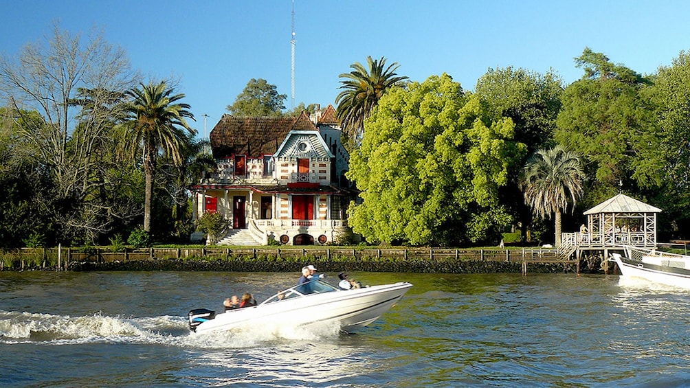View of a boat on the waters with a house in the back at the Island Town of Tigre