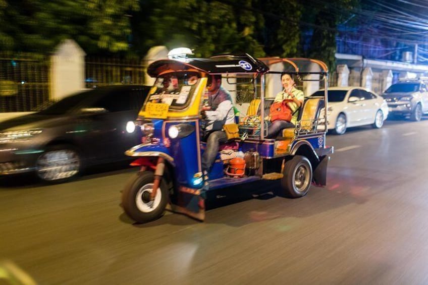 Tuk Tuk transports a tour guide through the streets of Bangkok on a midnight food tour, Thailand.