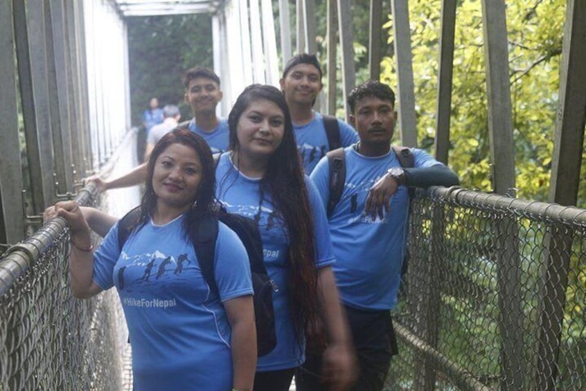 Hikers posing on a suspension bridge. 