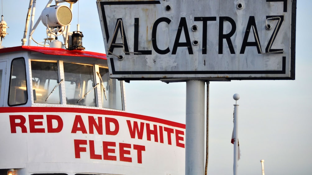 Weathered Alcatraz sign with cruise boat behind in San Francisco