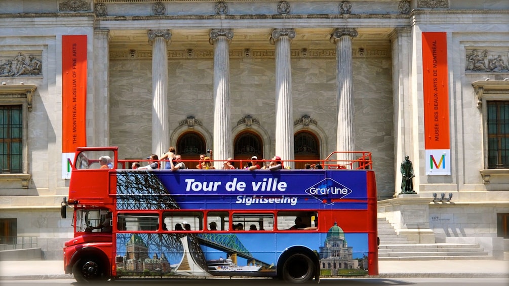 Red Hop On Hop off double-decker bus in front of the Montreal Museum of Fine Arts