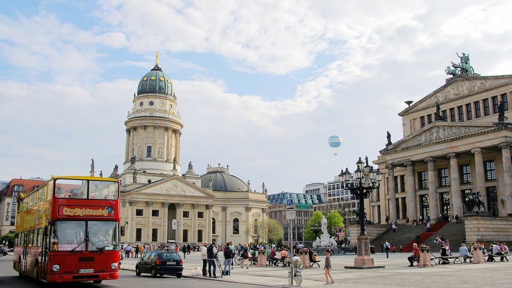 Show item 3 of 10. A hop on hop off bus driving past historical buildings in Berlin