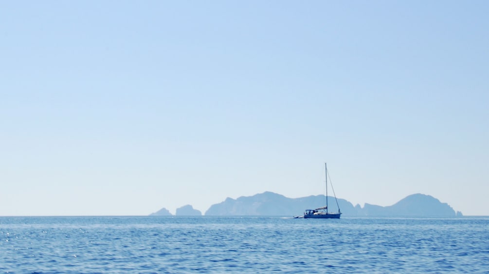 Landscape photo of the ocean view from Ponza Island with a sail boat off in the distance.