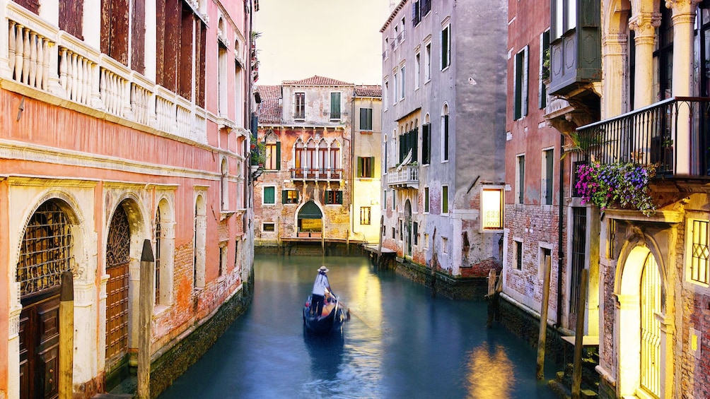 Passengers enjoying a peaceful ride on a gondola in the aisles of Venice.