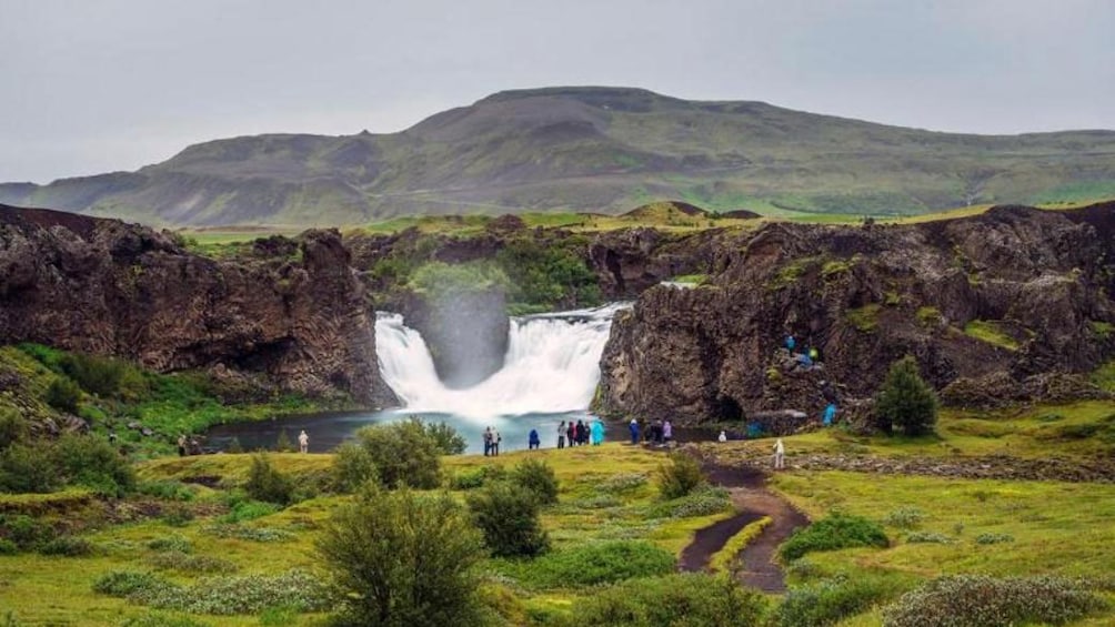 Tour group standing a a waterfall and pool in Reykjavik