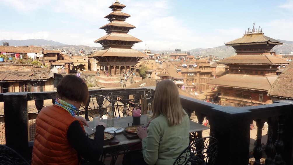 Show item 4 of 10. Two people enjoy lunch on a balcony with a view of Bhaktapur