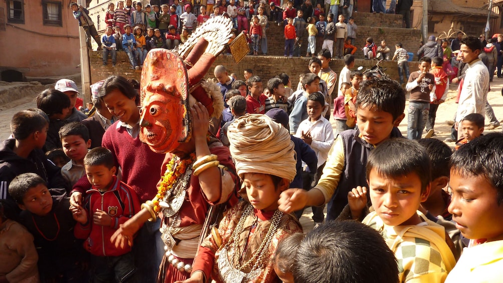 Show item 5 of 10. People dressed for a festival make their way down a street in Patan
