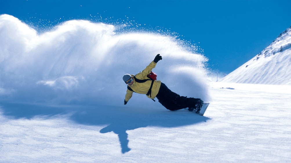 Flicking up snow while snowboarding down the slopes of Alta and Snowbird