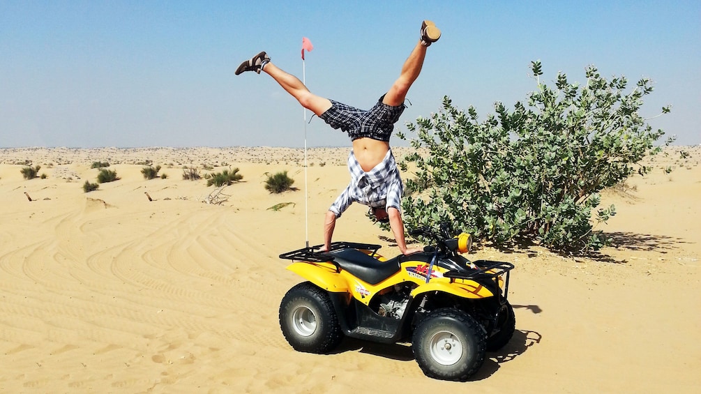 Man doing a handstand on a quad bike in the desert in Dubai