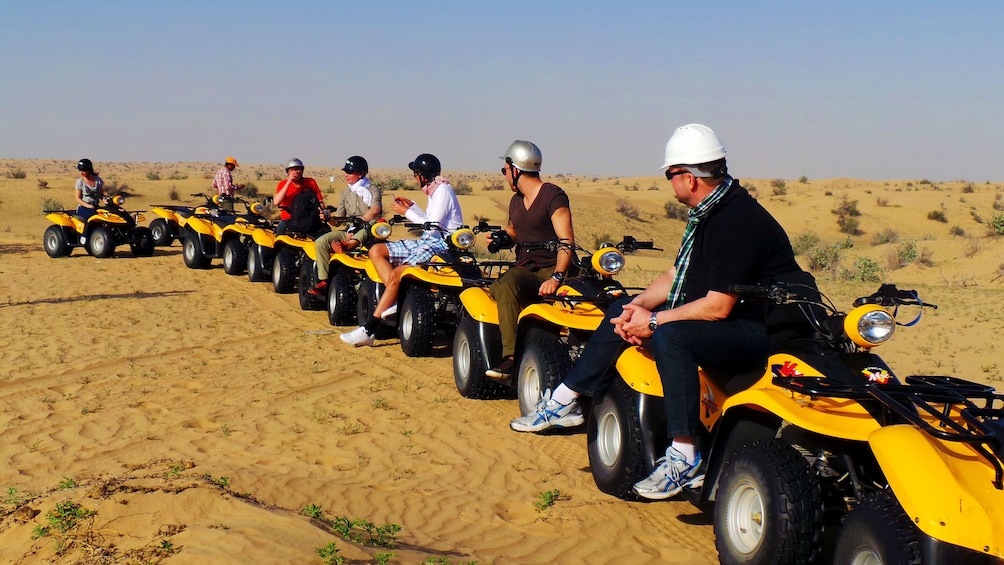 Group of people on quad bikes in a desert in dubai