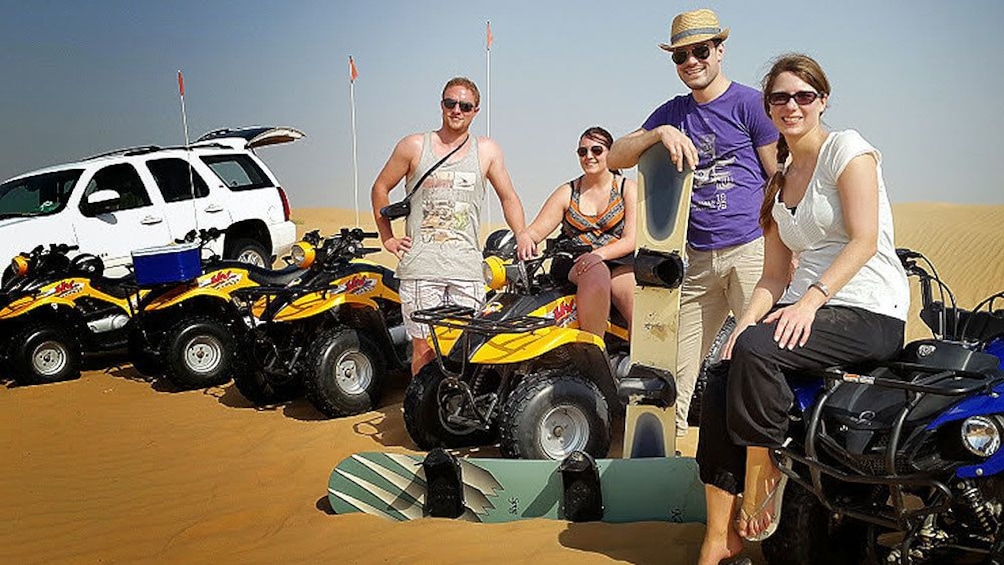 four people sit on ATV's on sand dunes in Dubai