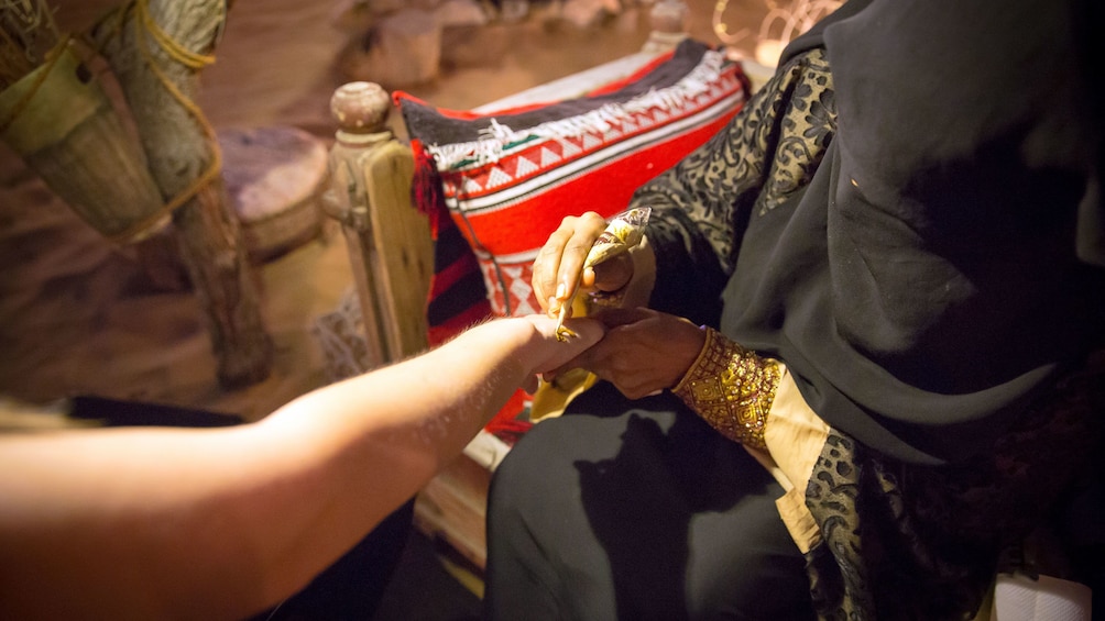 woman painting henna ink tattoos on arm in Dubai