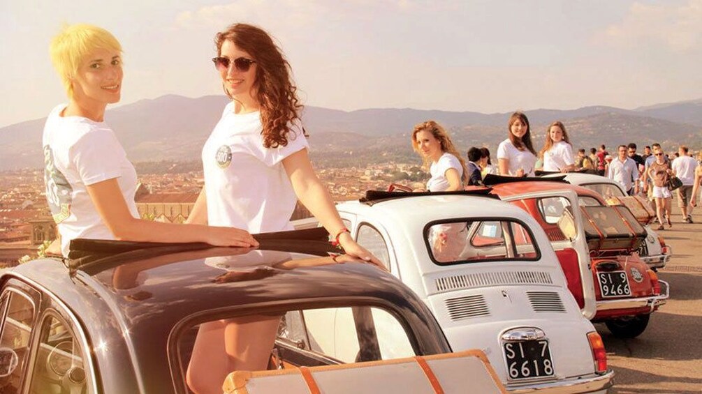 drivers and passengers pose with lined up Fiats in Siena