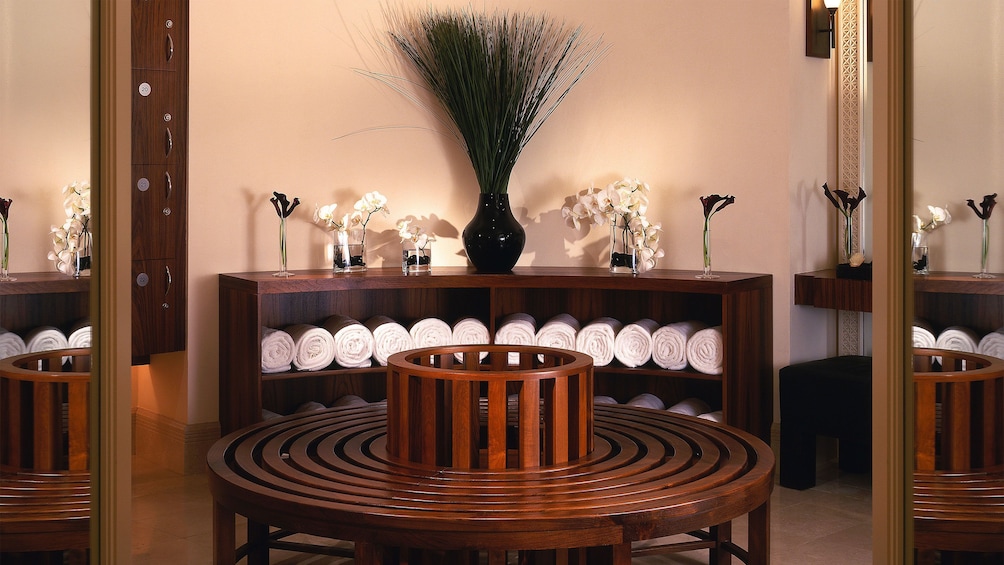 Show item 4 of 5. towels and orchids and wooden benches in spa in Abu Dhabi