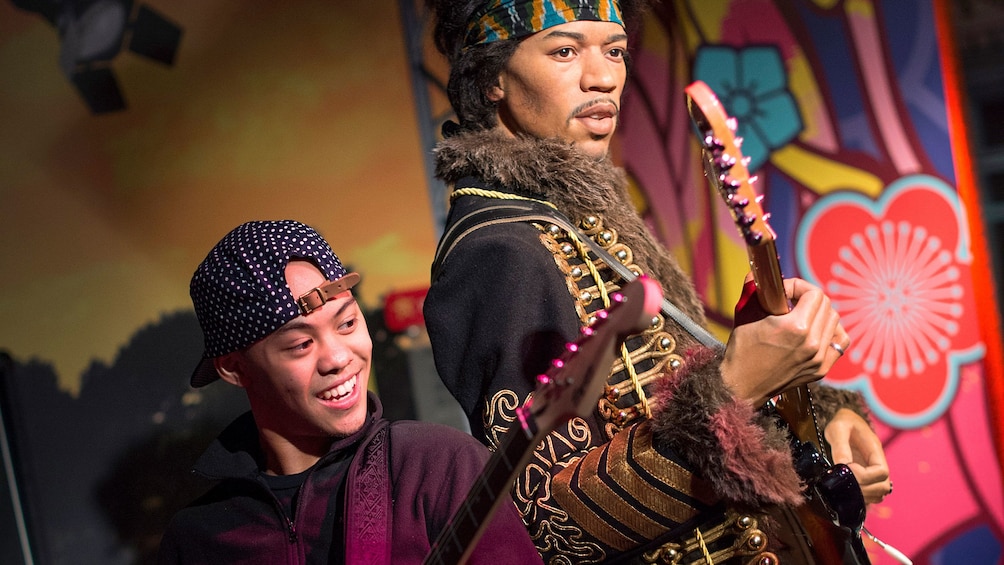 Show item 1 of 10. Boy playing guitar with Jimi Hendrix wax figure at Madam Tussauds in San Francisco