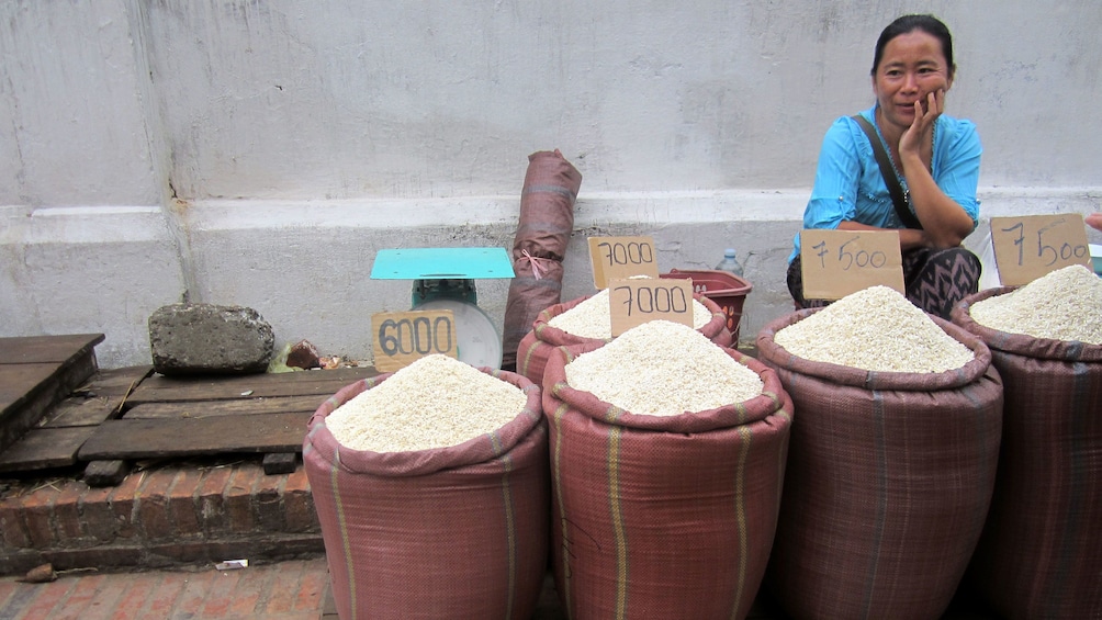 Woman selling different types of rice at a market in Luang Prabang