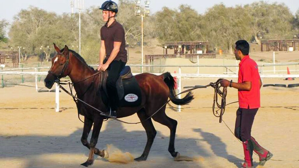 Instructor guiding a student on horseback in Dubai