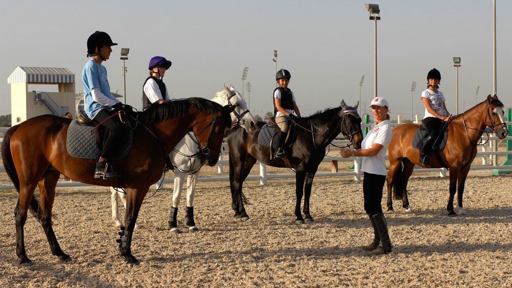 Instructor talking to students on horseback in Dubai