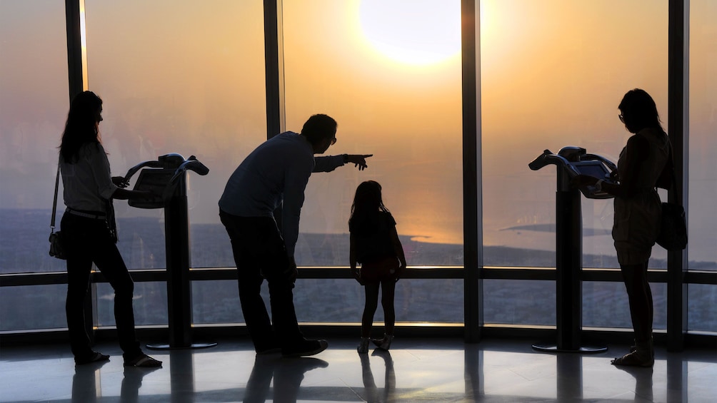 Family silhouetted at the observation deck at the Burj Khalifa at sunset in Dubai