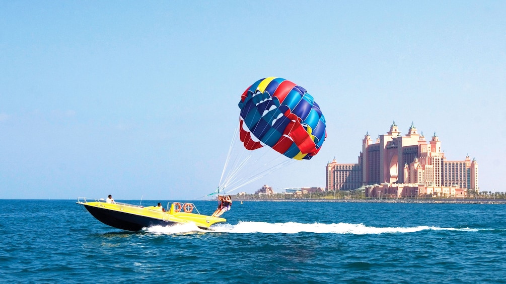 Jet boat with parasailers zipping past Atlantis Resort in Dubai