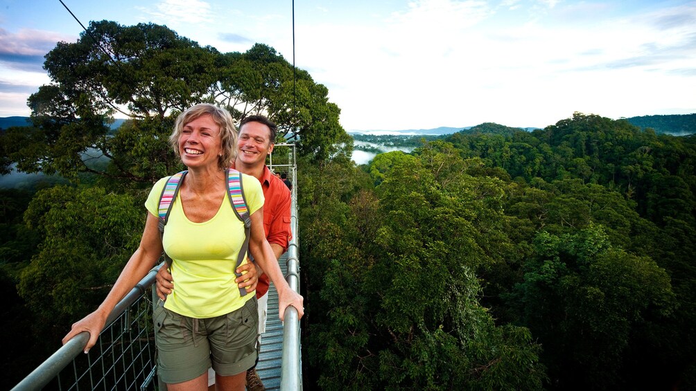 Show item 2 of 5. Couple enjoying the beautiful view of Ulu Temburong National Park on a suspension bridge